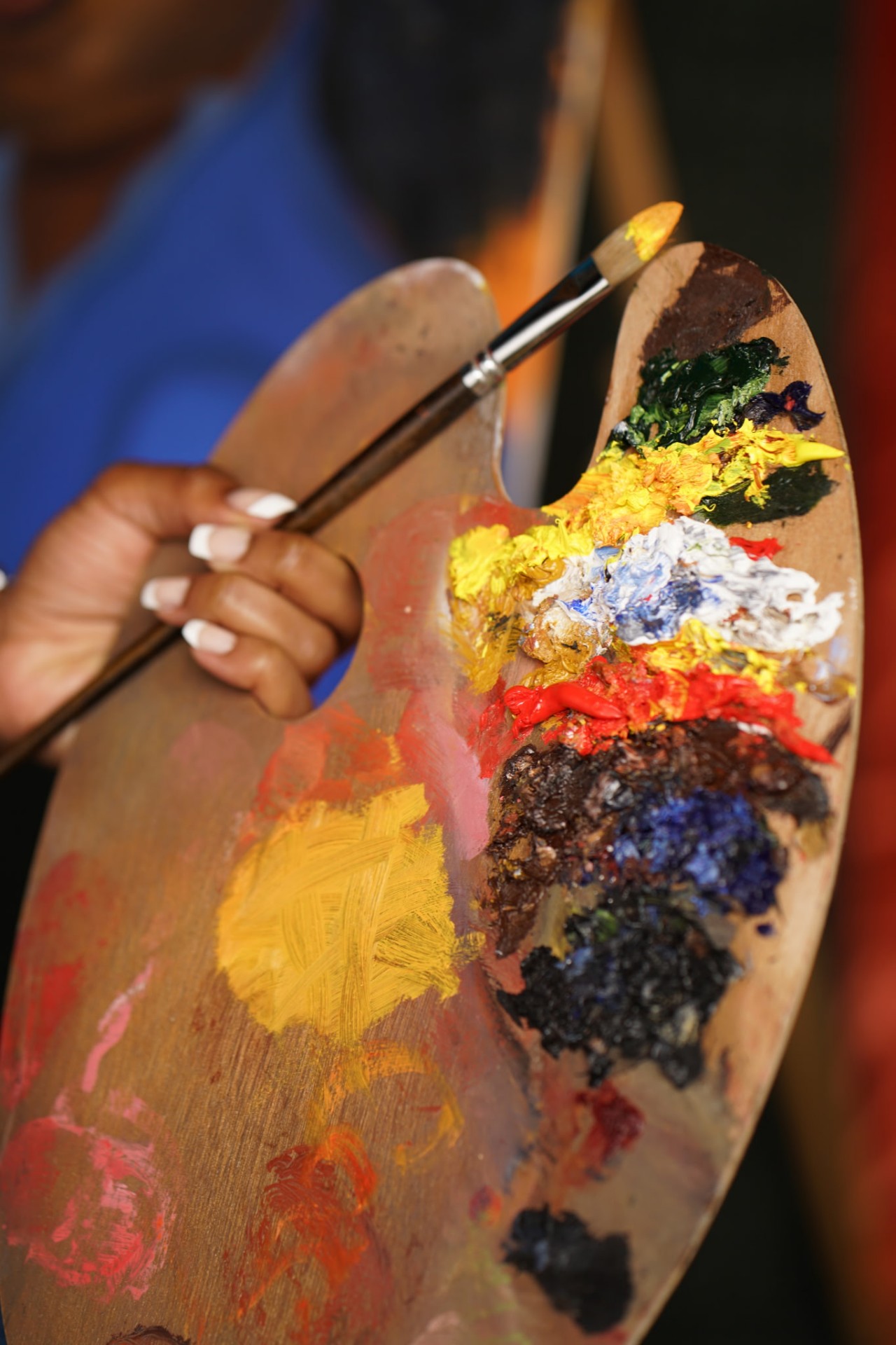 Close up of Carlynn's wooden oil palette loaded with yellow, red, cobalt and green paint